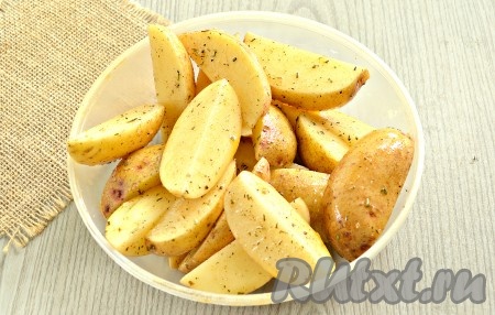Получившуюся смесь масла со специями вливаем к картофельным долькам, хорошо перемешиваем.