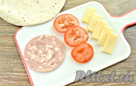 Отрезаем кусочек ветчины (или варёной колбасы). Сыр твёрдых сортов нарезаем тонкими ломтиками. Промываем помидор, тонко нарезаем его кружочками. Кстати, можно сразу поставить на огонь сковороду (лучше если это будет сковорода гриль).