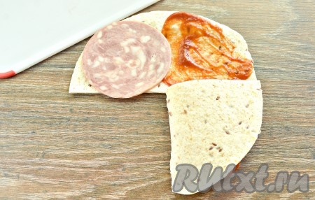 Начинаем собирать сэндвич. Поочередно сворачиваем части друг на друга (как на фото) так, чтобы начинка оказалась внутри тортильи.