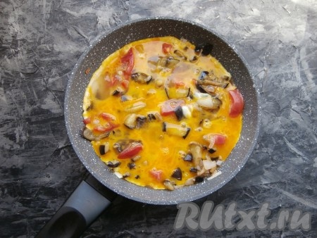 Баклажаны с помидорами, чесноком и луком перемешать, обжарить их минуты 3. Обжаренные овощи залить яйцами, смешанными с солью.