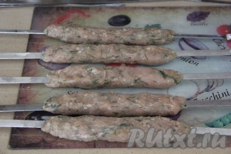 Охлаждённый фарш разделить на части (примерно, по 80-90 грамм каждая). Руками, смоченными в воде, распределить каждую часть фарша по шампуру, сформировав длинный люля-кебаб. У меня из указанного количества ингредиентов получилось 12 шампуров с куриными люля-кебабами. 