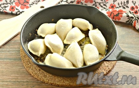 На сковороду с обжаренным луком выкладываем замороженные пельмени.