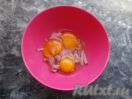 Колбасу нарезать брусочками (или соломкой), выложить в миску, добавить сырые яйца, перемешать.
