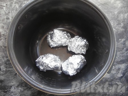 Поместить картошины, завёрнутые в фольгу, в чашу мультиварки и выставить программу "Выпечка" на 1 час. Крышку мультиварки закрыть.