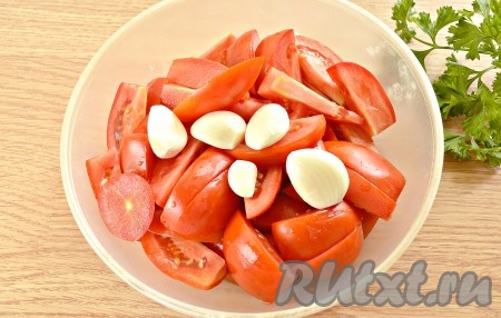 Промываем помидоры, затем вырезаем места, в которых росла плодоножка. Нарезаем помидоры на небольшие ломтики. Очищаем зубчики чеснока.