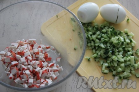 Вымытый огурец и размороженные крабовые палочки нарезать на мелкие кубики, сразу выложить в миску.