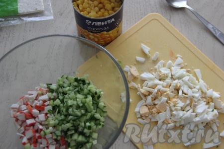 Яйца тоже нарезать на мелкие кубики и добавить в миску с огурчиками и крабовыми палочками.