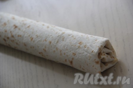 Края лаваша с двух более узких сторон слегка подвернуть, а затем, начиная с широкой стороны, свернуть лаваш в достаточно плотный рулет, завернуть в фольгу и отправить на час в холодильник.