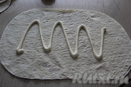 Нанести на лист лаваша майонез, затем равномерно размазать его по поверхности лаваша, оставляя чистыми края.