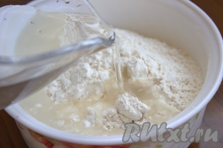 Влить в миску с мукой горячую воду и растительное масло.
