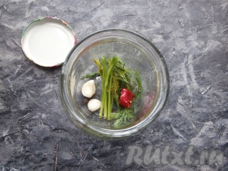 На дно чисто вымытой банки поместить укроп, зубчики чеснока, кусочек горького перца (можно с семечками) и душистый перец горошком.