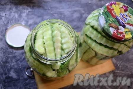 Залить огурцы в баночках крутым кипятком, накрыть прокипячёнными крышками и оставить на 15 минут.