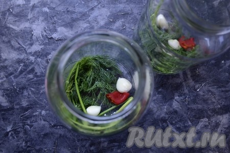 В чистые и сухие банки поместить по 2 веточки укропа, кусочку острого свежего перца и 2-3 зубчика чеснока.