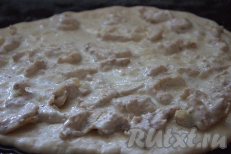 Подошедшее тесто разделить на 2 равные части (мы будем печь 2 пиццы "Жульен"). Одну часть теста выложить на рабочую поверхность, припылённую мукой, раскатать в пласт диаметром, примерно, 30-35 сантиметров и переложить на противень, застеленный бумагой для выпечки. Не забывайте, что мы будем готовить 2 пиццы, поэтому и ингредиенты для начинки нужно делить на 2 части. На тесто выложить половину остывшего куриного филе в сливочном соусе со сковороды.