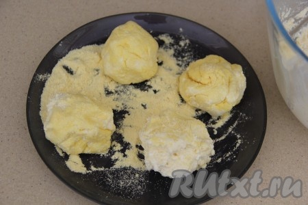 Из получившейся массы сформировать мокрыми руками заготовку сырника. На плоскую тарелку насыпать 1-2 столовых ложки кукурузной муки, обвалять в ней со всех сторон заготовку сырника. Аналогично сформировать и запанировать в кукурузной муке все сырники. Мне понадобилось около 1 столовой ложки муки на панировку сырников.