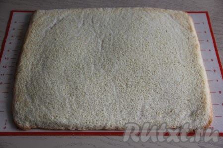 Выпекать бисквит минут 7-10 (до лёгкой румяности) в духовке, заранее прогретой до 200 градусов. Готовый бисквит вытащить из духовки, перевернуть на чистый силиконовый коврик (или на сухое полотенце) и снять пергамент.