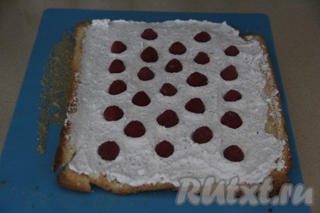 По прошествии часа развернуть бисквитный рулет и смазать крем-чизом, смешанным с шоколадом (вторую часть крема убрать в холодильник), сверху, по желанию, выложить вымытые и хорошо обсушенные ягоды.  