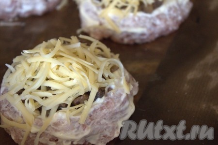 Затем в каждое углубление мясной ватрушки вложить часть остывшей грибной начинки. Сверху посыпать начинку натёртым сыром. Поставить противень с мясными ватрушками в разогретую духовку и запекать их минут 30-35 при температуре 180 градусов.