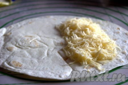 На одну половину тортильи, немного отступив от края, выложить часть сыра, натёртого на средней (или мелкой) тёрке.