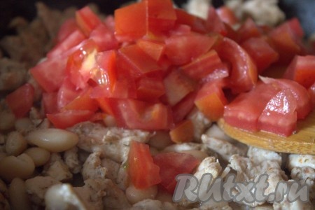 Далее в сковороду к куриному мясу и фасоли добавить помидор, нарезанный небольшими кубиками.
