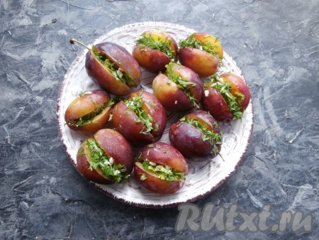 Зелень с чесноком перемешать и нафаршировать этой смесью сливы.