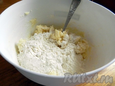К полученной массе добавить 1 стакан муки и разрыхлитель, растереть вилкой до однородности. Частями добавляя оставшуюся муку, вначале перемешивать тесто вилкой (или столовой ложкой). 