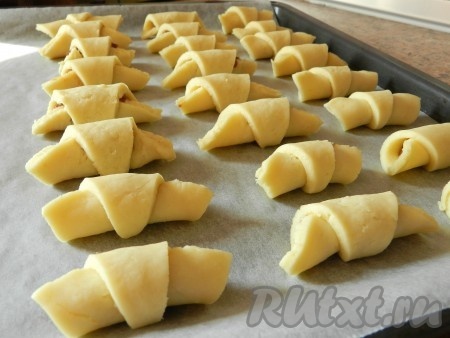 Скрученные рогалики из творожного теста выкладывать на противень, застеленный пергаментом. Яйцо слегка взбить вилкой, смазать поверхность рогаликов. Выпекать рогалики в духовке, разогретой до 190 градусов, 20 минут. Из указанного количества ингредиентов получается 32-34 рогалика.