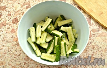 Огурцы промываем, срезаем кончики. Очищаем морковь. Из болгарского перца удаляем семена вместе с плодоножкой. Огурцы нарезаем небольшими брусочками и выкладываем в объёмную миску.