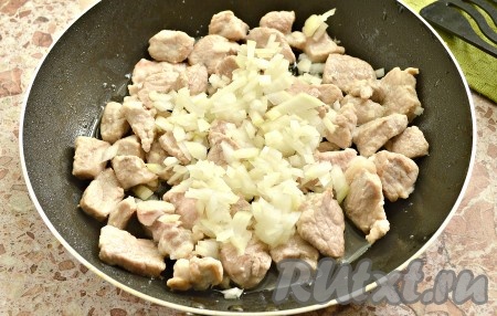 Очищаем лук, нарезаем его кусочками, выкладываем к обжаренной свинине и готовим на среднем огне минут 5, не забывая время от времени перемешивать содержимое сковороды.