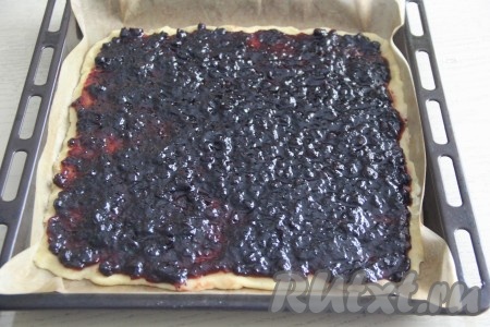 Выложить поверх теста варенье и распределить его равномерно по тесту.