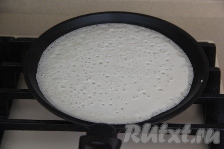 Смазать небольшим количеством масла сковороду перед жаркой первого блина, в дальнейшем сковородку можно не смазывать, ведь масло мы добавили в блинное тесто. На раскалённую сковороду влить половник теста и распределить по всей поверхности сковороды. Жарить блин на среднем огне, достаточно быстро его поверхность покроется мелкими дырочками, когда он снизу подрумянится, перевернуть его.