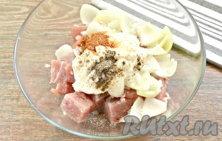 Обычно я мариную мясо в стеклянной большой миске (можно мариновать и в другой удобной объёмной посуде, например, в эмалированной или металлической кастрюле). Кусочки свинины выкладываем в миску (или другую посуду, в которой будете мариновать мясо), добавляем сметану, соль, обе нарезанные луковицы, чёрный молотый перец, паприку.