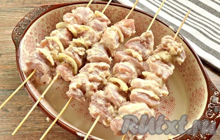 Деревянные шпажки следует минут на 30 опустить в холодную воду, чтобы они напитались влагой и не стали пригорать во время запекания шашлыка в духовке. Замаринованные в сметане кусочки свинины нанизываем вместе с лепестками лука на деревянные шпажки. Шпажки размещаем на жаропрочной форме подходящего размера.