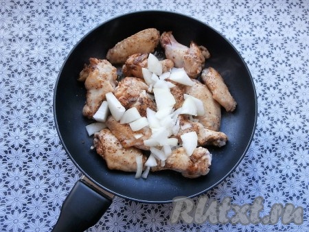 Масло разогреть в глубокой сковороде (я готовила на сковороде диаметром 26 см), выложить крылышки. Обжарить их на достаточно сильном огне до лёгкой румяности со всех сторон, после этого добавить очищенный и произвольно нарезанный лук.