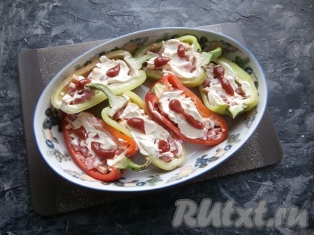 Разместить фаршированные половинки перцев в подходящей форме для запекания, смазать начинку сверху оставшейся сметаной и томатным соусом. Влить в форму растительное масло.