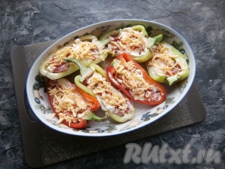 Фаршированные перцы посыпать оставшимся сыром, натёртым на мелкой (или средней) тёрке.