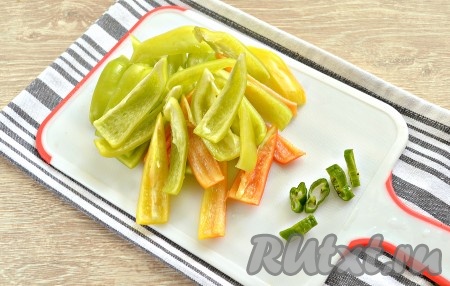 Нарезаем сладкий перец на лепестки среднего размера. Горький перец без семян нарезаем колечками.