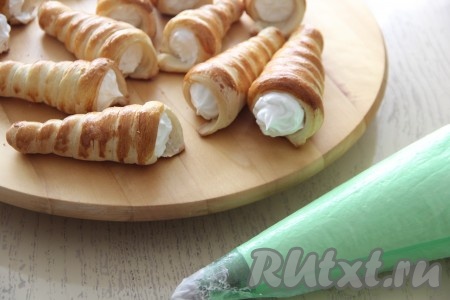 Белковый крем переложить в кулинарный мешок с фигурной насадкой и наполнить им слоёные трубочки.