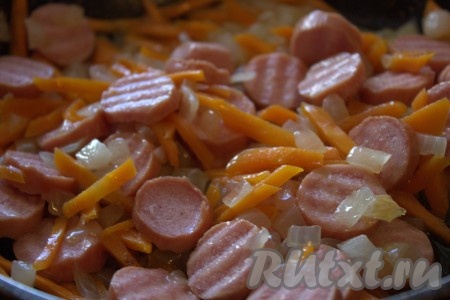 С сосисок снять плёнку (если она имеется), нарезать кружочками (очень тонко нарезать не нужно). Добавить сосиски в сковороду к овощам, перемешать хорошо и обжаривать на среднем огне минуты 3.