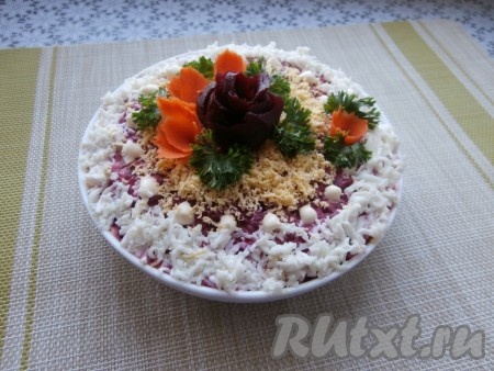 Дать салату "Селёдка под шубой" пропитаться в холодильнике минимум в течение 2 часов. Оставшееся варёное яйцо разделить на белок и желток. Белок и желток в разные ёмкости натереть на мелкой тёрке. Пропитавшийся салат украсить натёртыми белком и желтком, зеленью, цветочками из свеклы и моркови.