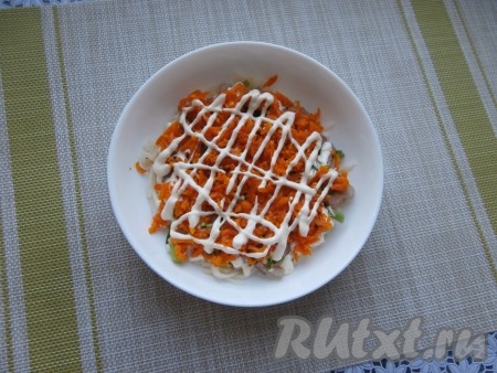 Следующим слоем выложить половину натёртой морковки, нанести сеточку из майонеза.