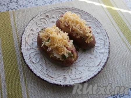 Наполнить получившейся массой клубни картофеля, а сверху выложить оставшийся натёртый сыр. 