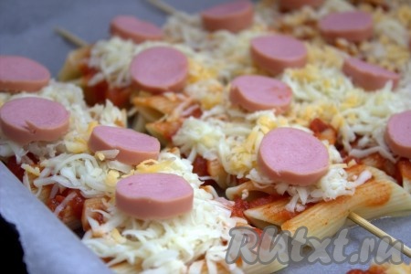 Затем выложить на сыр очищенные от плёнки и нарезанные на кружочки сосиски.