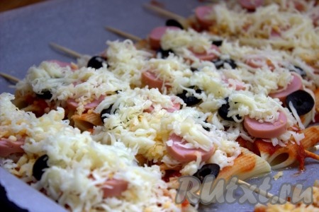 Затем сверху присыпать шпажки с макаронами и сосисками оставшимся сыром.