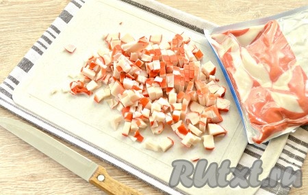 Прежде всего отвариваем яйца для салата в течение минут 8-10 с момента начала кипения воды, затем остужаем их в ледяной воде, а потом очищаем. С чесночных зубчиков удаляем шелуху. Петрушку и огурец промываем и обсушиваем. Крабовое мясо нарезаем на мелкие кубики, сразу перекладываем в достаточно объёмную миску, в которую в дальнейшем будем выкладывать все ингредиенты.