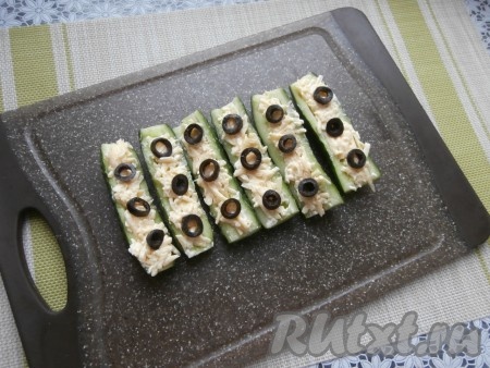 Украсить огурчики кружочками оливок.