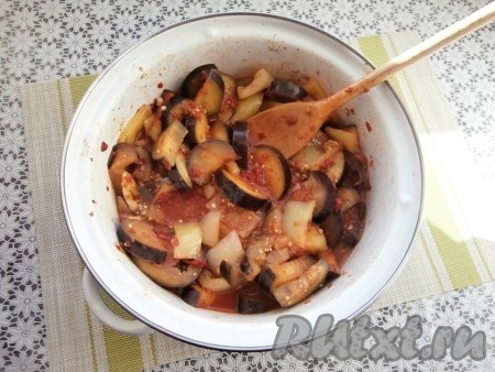 Накрыть кастрюлю крышкой, довести содержимое до кипения, а затем тушить баклажаны с болгарским перцем и чесноком в томате на небольшом огне 25-30 минут. Когда баклажаны обмякнут, нужно всё перемешать.