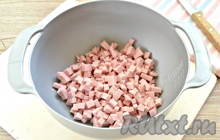 Заранее для оливье отвариваем в кожуре морковь и картофель (обычно на их отваривание требуется минут 25-30 с начала кипения воды, готовность можно проверить достаточно просто - нож в готовые корнеплоды будет входить легко), затем воду, в которой варились овощи, сливаем, остужаем их и очищаем. Отвариваем вкрутую куриные яйца (варим их с момента начала кипения воды минут 8-10), остужаем их в холодной воде и очищаем. Порядок измельчения ингредиентов для оливье особой роли не играет, главное - это нарезать ингредиенты на, примерно, одинаковые по размеру кубики. Размер кубиков выбирайте на своё усмотрение, я предпочитаю нарезать на мелкие кубики, мне кажется, что в таком виде салат получается более вкусным. Колбасу нарезаем на мелкие кубики и сразу выкладываем в глубокую миску.