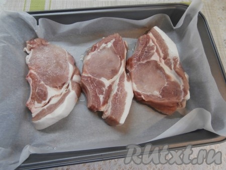 Противень застелить пергаментом и смазать небольшим количеством растительного масла. Отрезать пергамент так, чтобы часть его оказалась за противнем и длины этой части хватало, чтобы накрыть весь противень сверху. Стейки корейки разместить на противне.