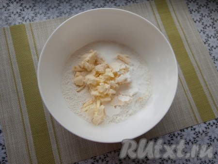 В достаточно объёмную миску просеять муку, всыпать разрыхлитель, соль, сахар и добавить охлаждённое сливочное масло, предварительно нарезанное на небольшие кусочки.